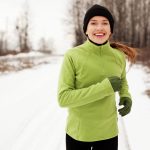 woman smiling and running on a trail in winter