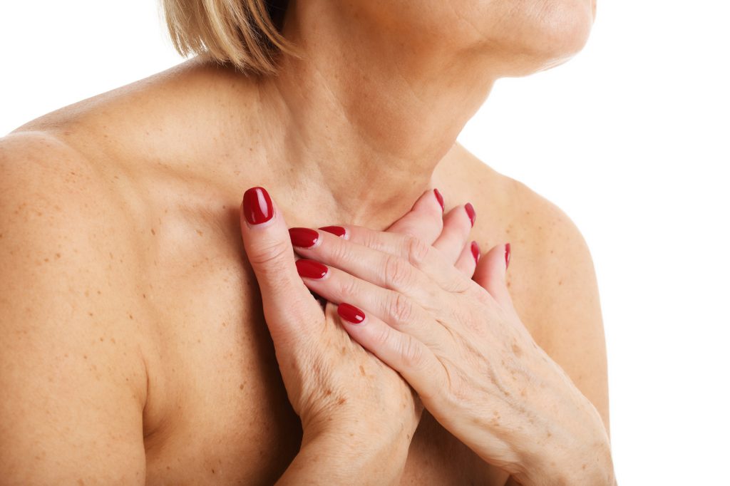 Woman covering age spots on chest.