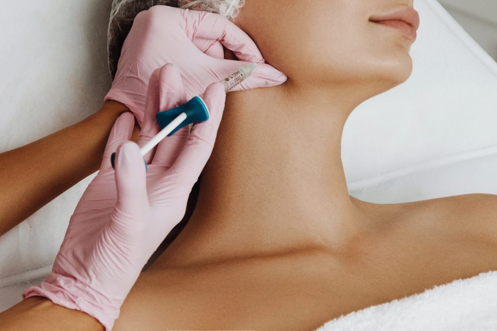 Woman getting dermal filler injection in jaw.