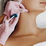 Woman getting dermal filler injection in jaw.