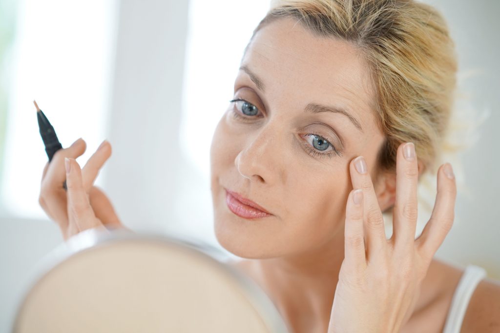 Middle aged woman applying makeup. 